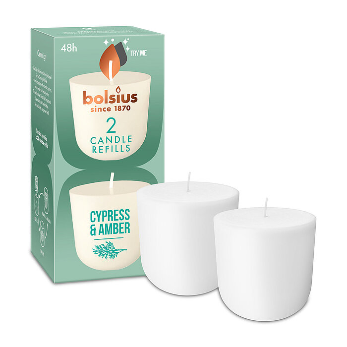 Zwei Cleanlight Duftkerzen-Nachfüller mit Zypresse/Amber-Duft stehen neben der dazugehörigen grünen Verpackung mit Bolsius Schriftzug.