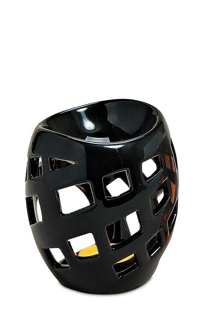 Ein dekorativer Teelichthalter aus glänzend schwarzer Keramik mit einem modernen, geometrischen Design. Die Oberfläche ist durchbrochen mit verschieden großen Rechtecken, die das Licht durchlassen. Innen sieht man ein sanftes, warmes Licht einer brennende