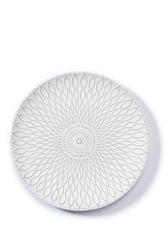 Ein rundes, weißes Keramiktablett mit einem filigranen, symmetrischen Muster, das von der Mitte nach außen verläuft. Das Design erinnert an feine, geschwungene Linien, die ein elegantes, organisches Muster bilden. Die subtile Textur und die dezente Farbge