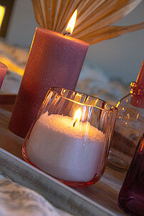 Nahaufnahme eines selbstgemachten Kerzenglases, bestehend aus einem rosa Teelichtglas von Sandra Rich und Wachsgranualt von Wenzel.