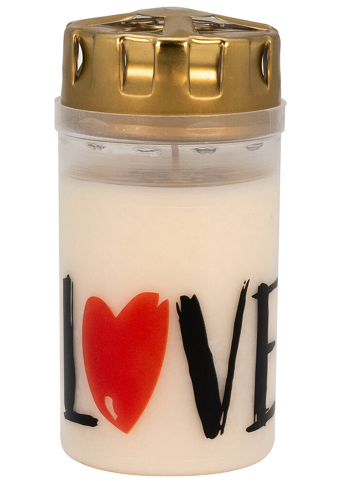 Eine weiße Kerze mit einem roten Herz und den schwarzen Buchstaben "L", "V", "E", die zusammen das Wort "LOVE" bilden. Die Kerze hat einen goldenen Deckel. Die Aufmachung vermittelt eine romantische und liebevolle Stimmung.