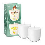 Zwei Cleanlight Duftkerzen-Nachfüller mit Grapefruit/Ingwer-Duft stehen neben der dazugehörigen grünen Verpackung mit Bolsius Schriftzug.